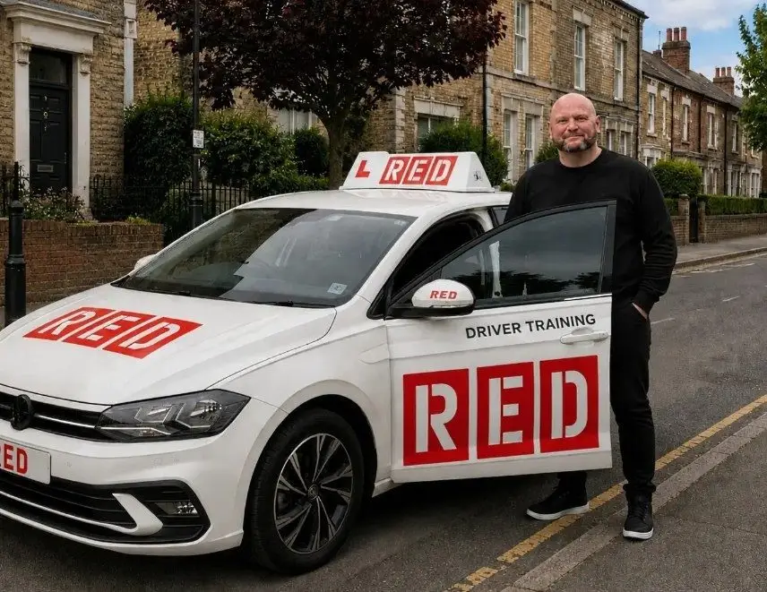 Mick Letts standing beside his Volkswagen Polo learner car